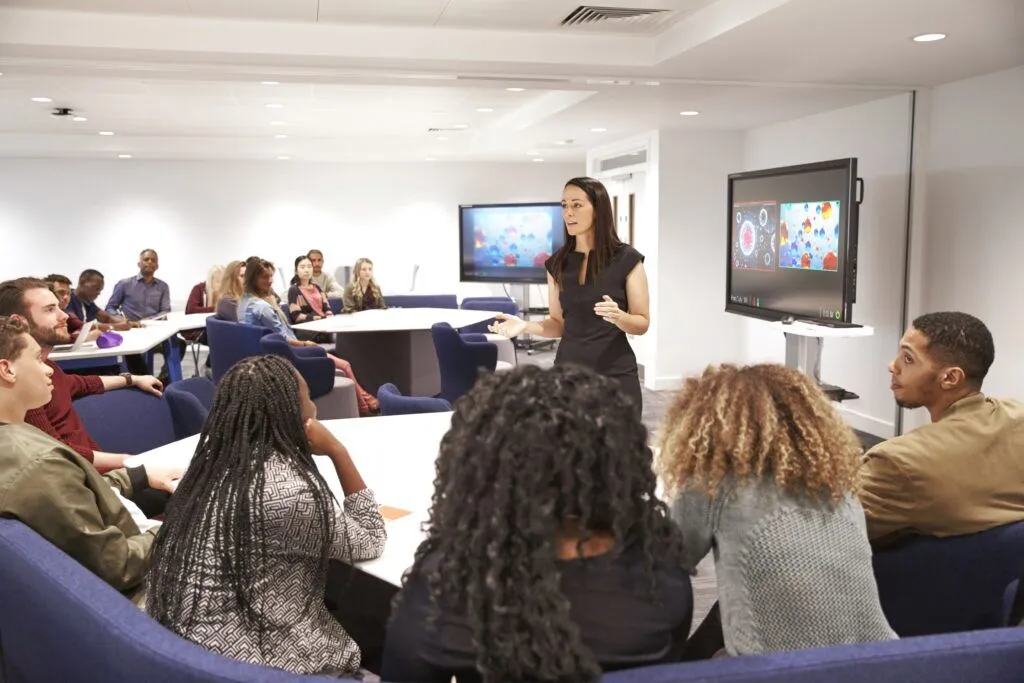 An active-learning room: displays at team tables, and the teaching surface treated as one room rather than as several screens.